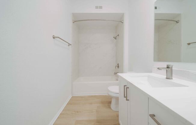 A white bathroom with a toilet, sink, and bathtub.