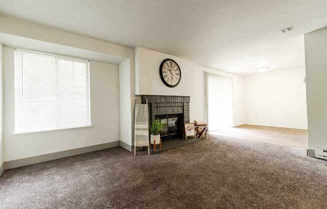 A living room with a fireplace and a clock on the wall. at Crown Pointe, Lakewood, WA, 98499