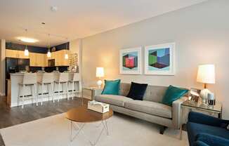 a living room with a couch coffee table and a kitchen in the background