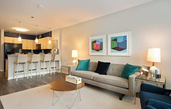 a living room with a couch coffee table and a kitchen in the background