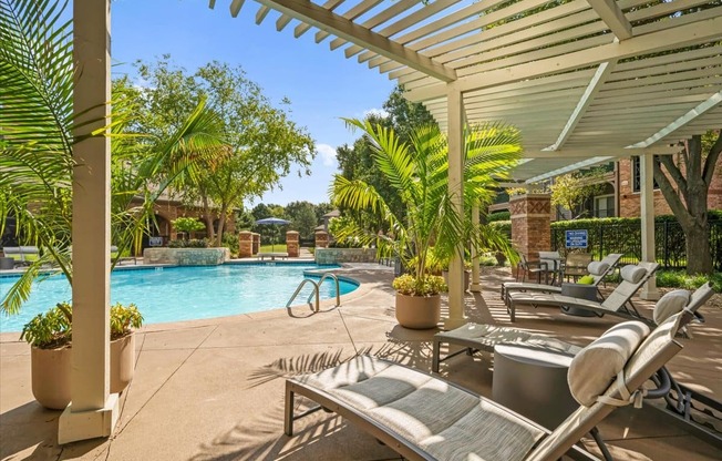 A pool surrounded by palm trees and lounge chairs.