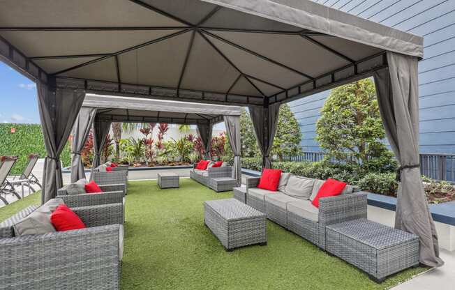 a lounge area with couches and chairs under a gazebo