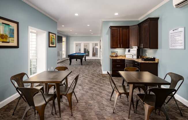 a room with a table and chairs and a pool table in the background