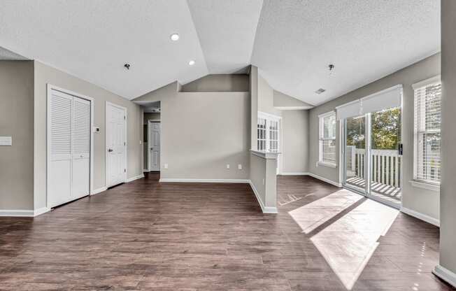 an empty living room with windows and a balcony