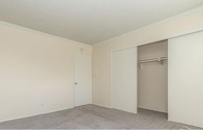 an empty bedroom with a closet and a door to the wardrobe at Villa La Paz Apartments, Bellflower, CA, 90706