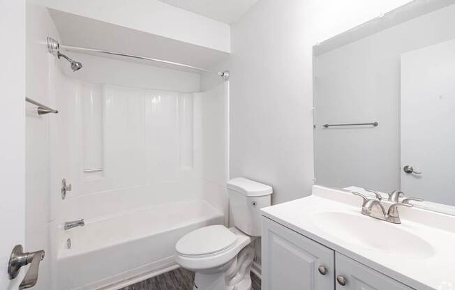 A white bathroom with a toilet, sink, and bathtub.