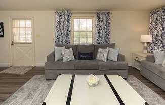 A grey couch with a white coffee table in front of it.