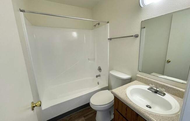 A white bathroom with a toilet, sink, and bathtub.