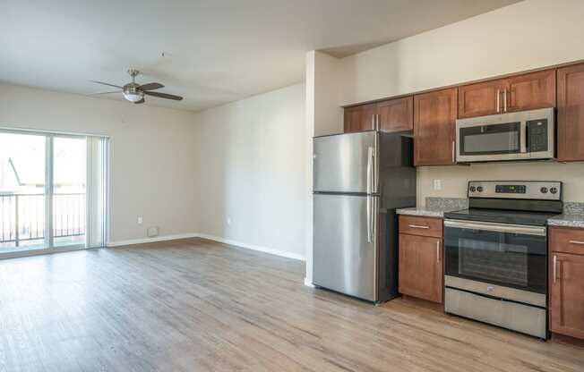 an empty kitchen with stainless steel appliances and wooden cabinets