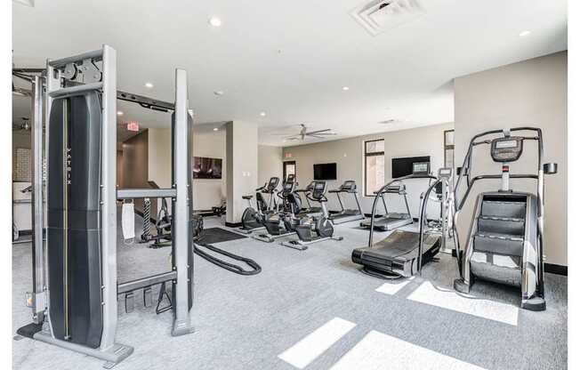 A gym with a variety of equipment including a treadmill, weights, and a bench press.