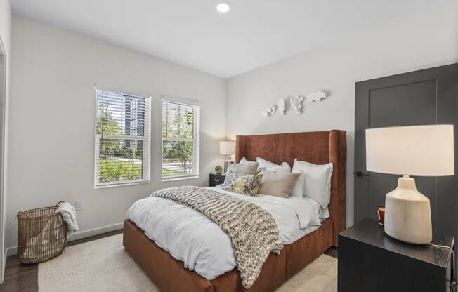 A bedroom with a large bed and a lamp on a side table.