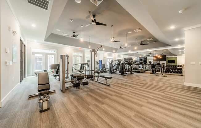 a gym with cardio equipment and weights on a wooden floor