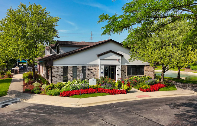 A church with a cross on the roof is surrounded by greenery and flowers.