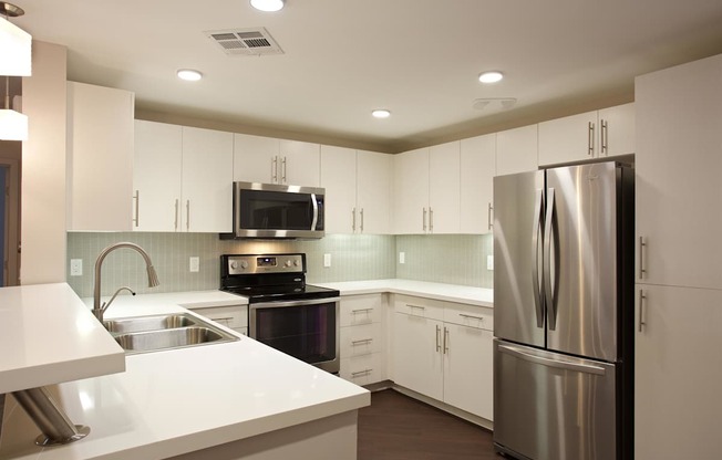 A modern kitchen with white cabinets and stainless steel appliances.