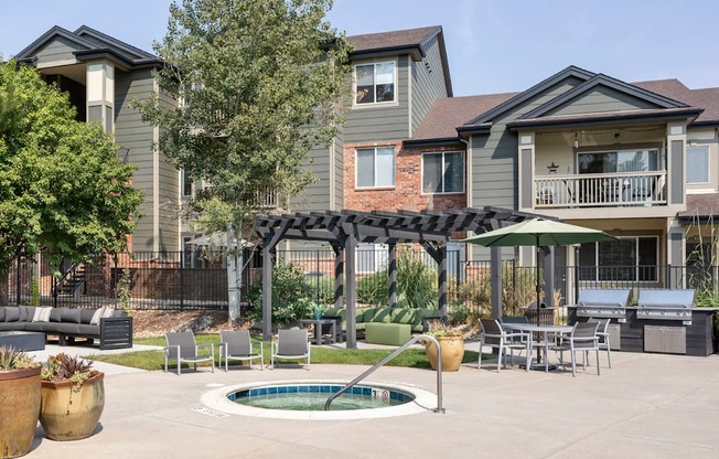 A patio with a hot tub and chairs is surrounded by houses.