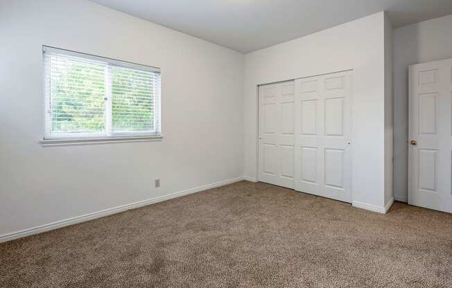 Bedroom with window, carpet flooring, and closet space