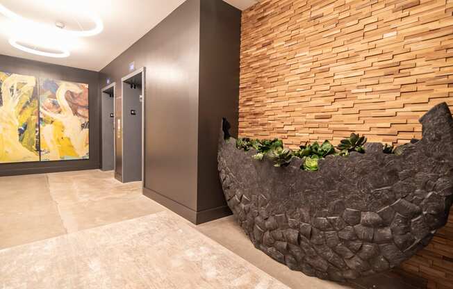 a rock wall in a hallway with a door and a painting