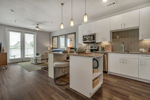 A modern kitchen with white cabinets and a wooden floor.