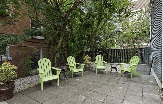 a patio with four green Adirondack chairs and a small table  at Charbern Apartment Homes, Seattle, WA