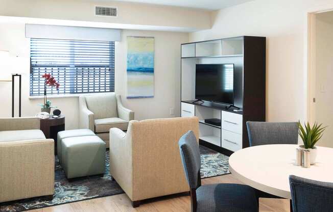 a living room with chairs and a table and a television at Parks Residential - Denver, Centennial, 80111