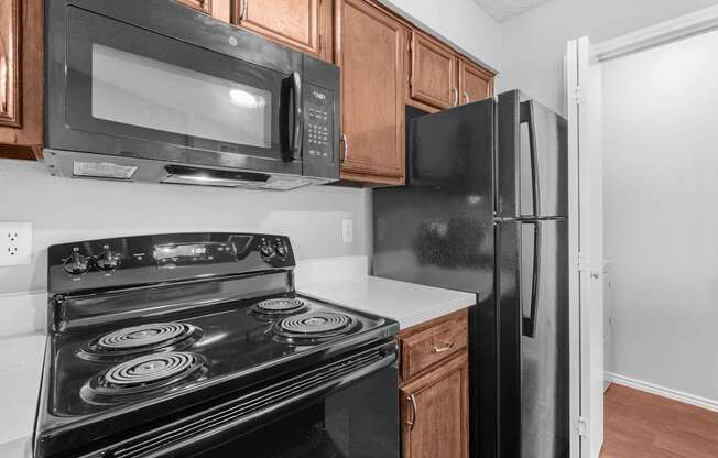 A black stove and microwave in a kitchen with wooden cabinets.