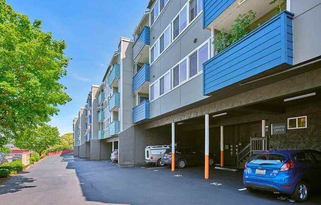 Apartments with carports, access to the leading office to the right, and mailboxes and trees on the left.