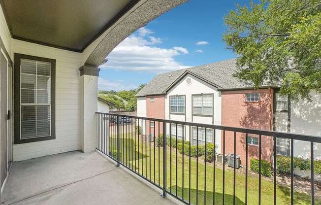 A balcony with a black railing and a view of a red brick house.