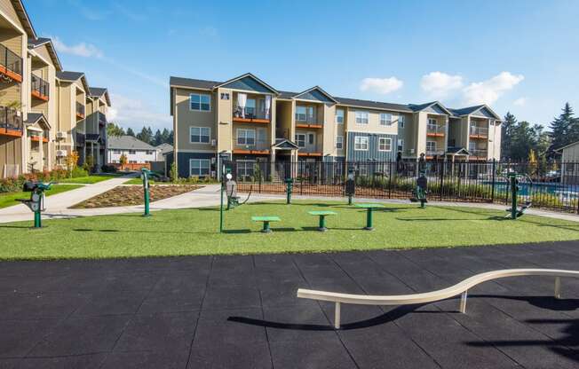 an empty park with a playground in front of an apartment building