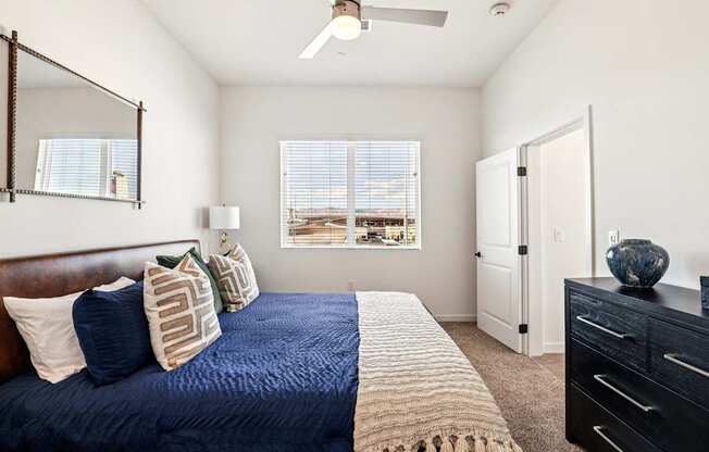 A bedroom with a bed, dresser, and window.