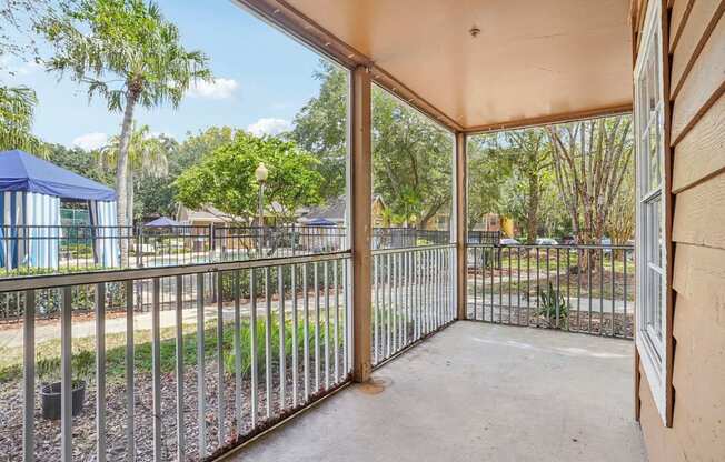 A patio with a metal railing and a view of a park.