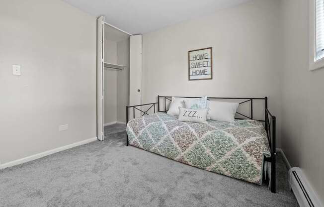 A bedroom with a bed, pillows, and a framed picture on the wall.
