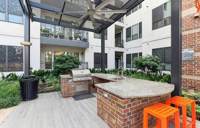 A patio with a barbecue and orange stools.