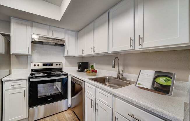 a kitchen with white cabinets and appliances and a sink