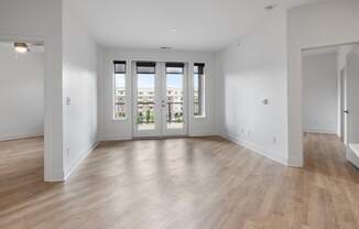 a living room with white walls and a door to a balcony