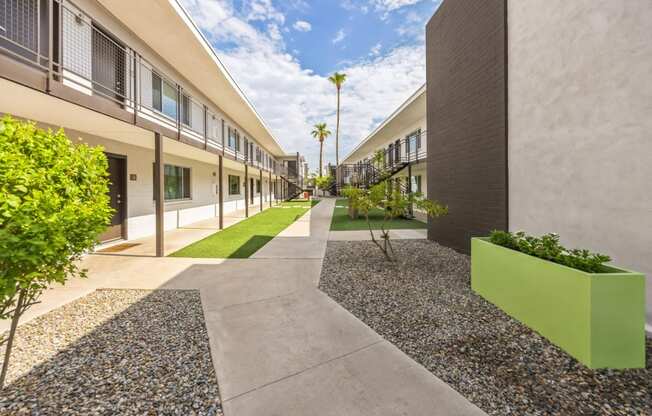 a courtyard between two buildings with grass and plants on the side of it