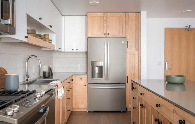 a kitchen with wooden cabinets and a stainless steel refrigerator at Slabtown Square Apartments, Portland ,Oregon, 97209