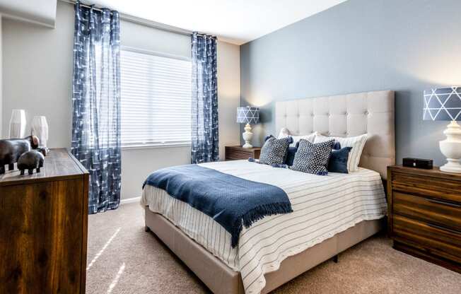 a bedroom with a bed and a window with blue curtains at The links at Plum Creek Apartments, Castlerock Colorado