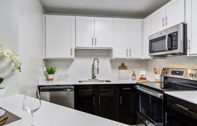 a kitchen with white cabinets and black appliances and a white counter top