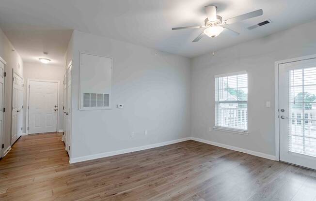 A spacious room with a ceiling fan and hardwood floors.