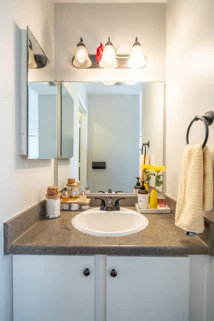 A bathroom with a sink, mirror, and lights.