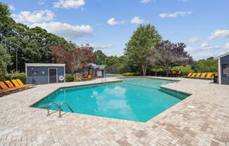 a swimming pool with lounge chairs and trees in the background at Woodcreek Apartments, Cary, 27511