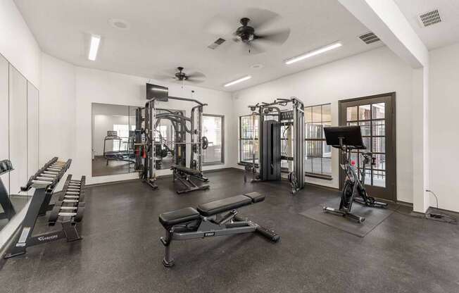 A spacious gym with a variety of equipment including a treadmill, weights, and a bench press.