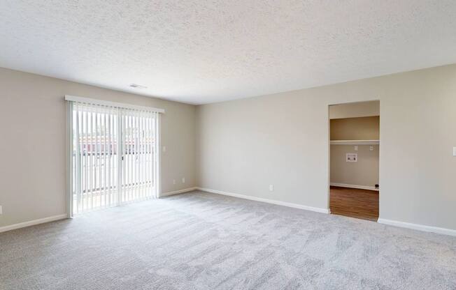 the spacious living room and dining room of an empty home with a sliding glass door