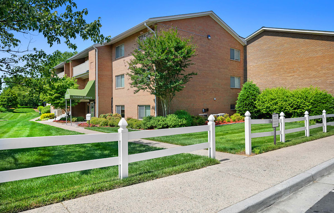 a white fence in front of a brick building