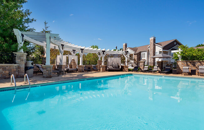 a swimming pool with a pergola over it and a house in the background