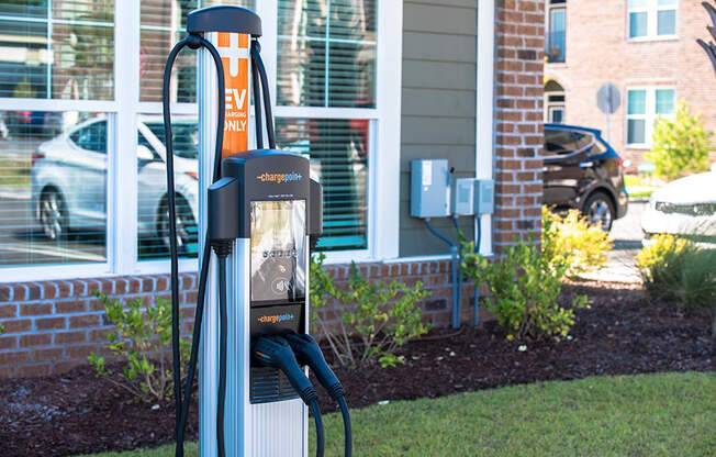 a gas pump in the grass in front of a building