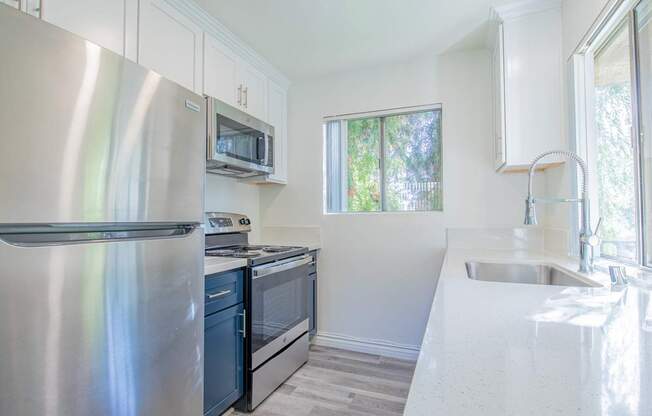 A kitchen with a stainless steel refrigerator, microwave, oven, and sink.