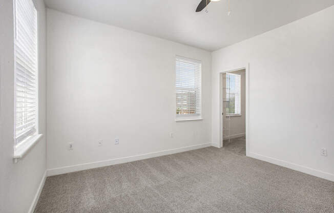 A bedroom with a carpeted floor and windows with blinds at Meadowbrooke Apartment Homes in Kentwood, MI 49512