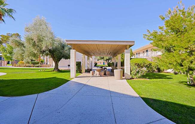 A pavement leads to a pavilion with a roof supported by four pillars.