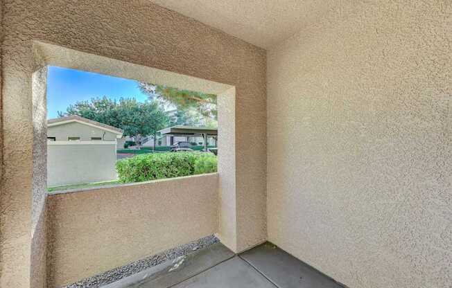 A view of a house through a window in a room with beige walls.